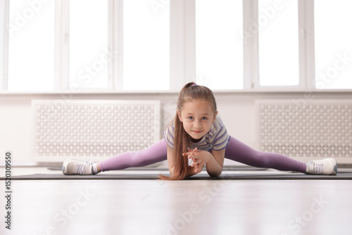 Cute girl practicing yoga on mat indoors