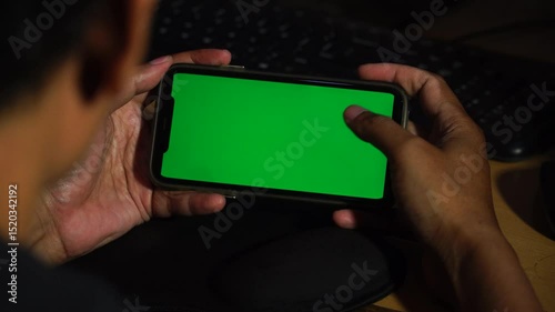 Man holds and swipes smartphone screen with chroma green screen