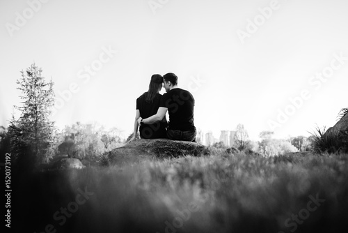 Couple enjoying a peaceful moment on a rock during sunset in nature