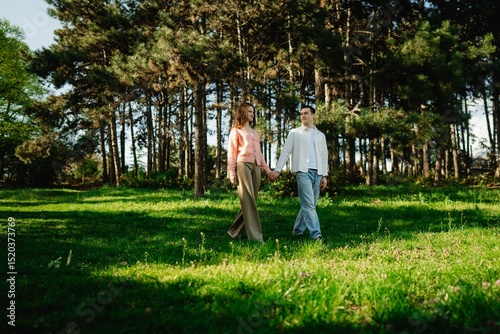 Young couple enjoys a romantic stroll through a sunlit forest clearing
