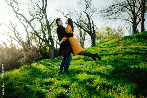Couple enjoys a joyful embrace in a sunlit green field during spring