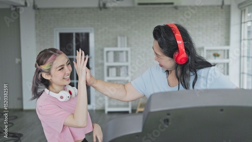 Mother hands high five with daughter after exercising on a treadmill, Healthy Living Concept