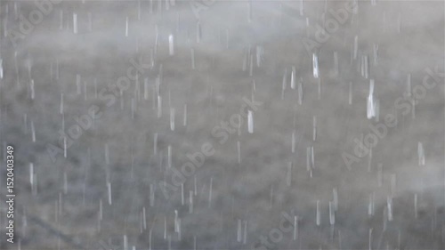 Close-up view of raindrops, in the background drops fall on a flooded street