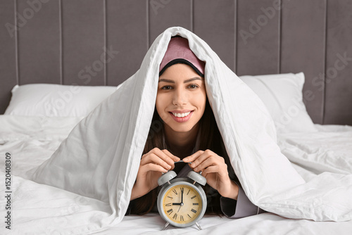 Young woman under blanket w...