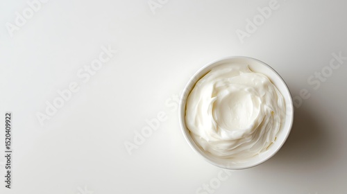Top down view of a bowl filled with creamy white substance against a white background area
