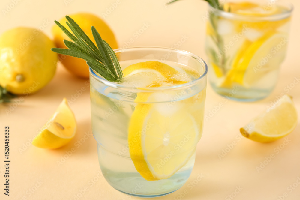 Fototapeta premium Glasses of fresh lemonade with rosemary and lemons on beige background, closeup