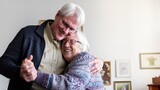 Senior couple dancing and hugging, smiling warmly. Elderly joy, elderly love, and elderly happiness fill the room. A heartwarming elderly moment. Senior couple dancing together in retirement home.