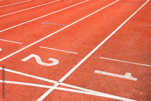Red running track with numbered starting lines outdoor for organizing sports competitions and exercising for health.