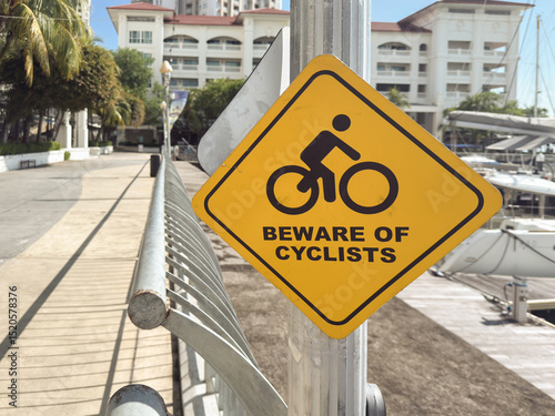 Yellow warning sign for cyclists near marina in Penang Malaysia highlighting safety for pedestrians