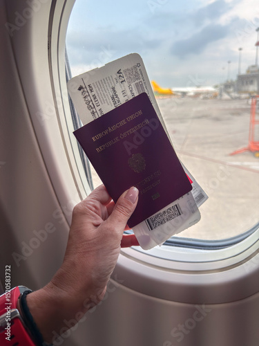 Holding a passport and boarding pass by the window on a flight