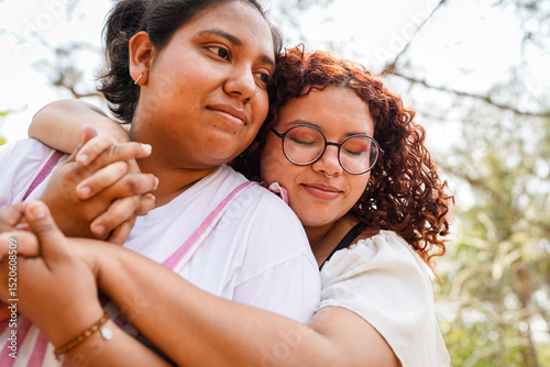 Two latin women embracing and holding hands in a park