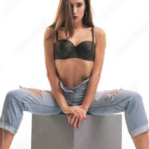 Model poses in stylish lingerie and ripped jeans for a fashion shoot