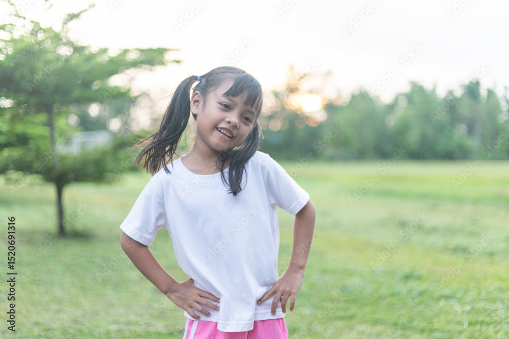 A young girl stands on a grass field warming up before exercising and has a smile on her face. A young girl stands on a grass field warming up before exercising and has a smile on her face.
