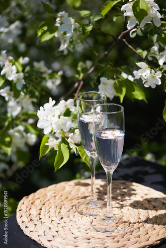 Sparkling drinks served on a woven mat amidst blooming white flowers