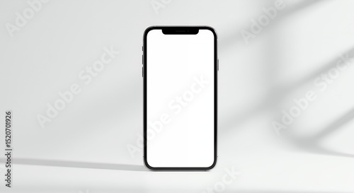 Smartphone with blank screen standing on white surface with soft window light
