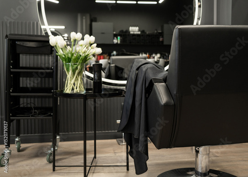 Fototapeta Naklejka Na Ścianę i Meble -  Modern barbershop interior with black salon chair and tulip arrangement