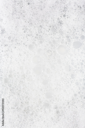 Bubbles create a textured appearance on a surface during a cleaning process in bright lighting
