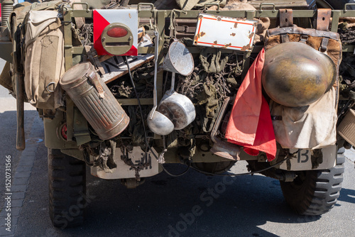 military truck is covered in various items, including a red flag and a metal container. The scene is chaotic and disorganized,