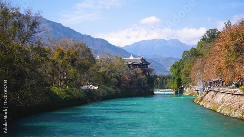 A traditional Chinese-style pavilion or temple nestled among trees with a clear river at Dujiangyan, Sichuan, China 