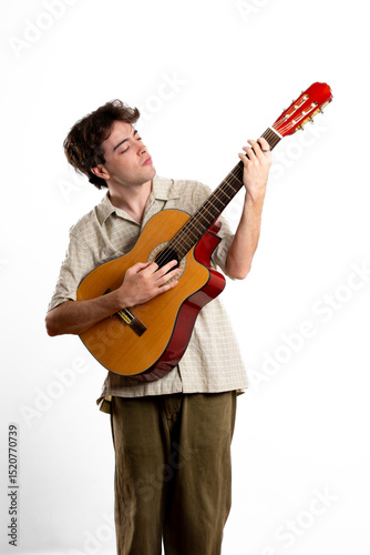 Concentrated young Latin man in a photographic studio, practicing with the guitar