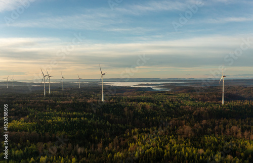 Drone view with wind turbines in a german forest at golden hour at sunrise