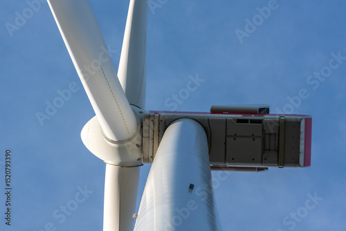 Modern wind turbine close-up, isolated on the blue sky, low angle view