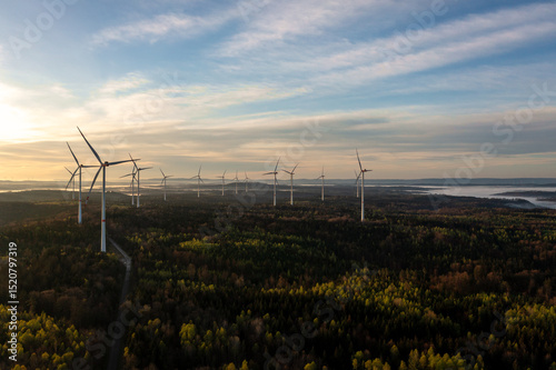 Wind turbine in forest at sunrise, drone aerial view