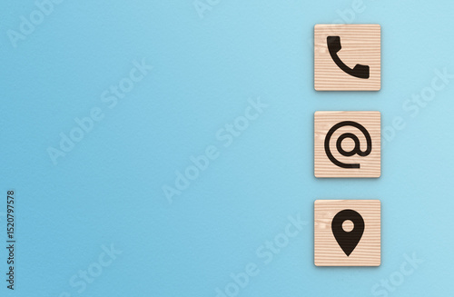 Contact Us background. Telephone, envelope letter and location icons on wooden blocks with copy space blue background