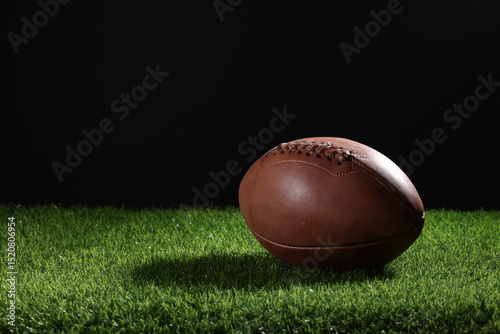 Fotografie A textured American football resting on the green artificial turf with white line