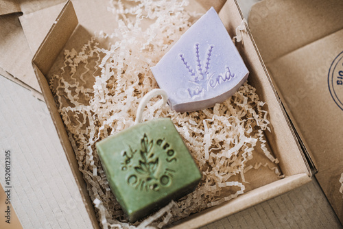 Open kraft box with green olive oil soap and lavender bar on shredded filler. Herbal cosmetics, plant-based skincare, olive oil soap, natural beauty products