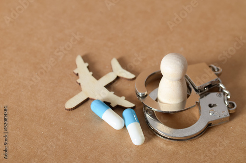 Drug Trafficking Concept with Airplane, Capsules, Handcuffs, and Wooden Figure Representing Arrest