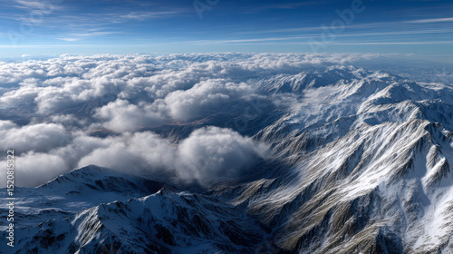 Breathtaking mountain landscape with snow capped peaks and fluffy clouds, showcasing nature beauty and serenity