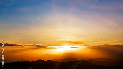Golden sun dips below the mountain horizon, painting the evening sky with beautiful orange and red light