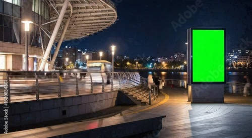 Time lapse video of a green screen billboard at night with blurred cars and people passing by. The billboard is ideal for advertising and marketing campaigns.