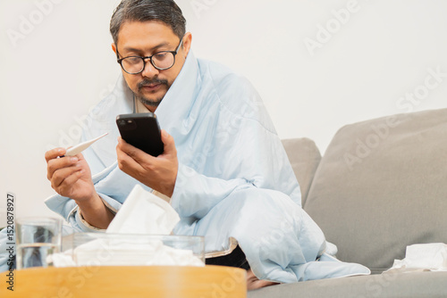 High temperature concept. Man feels serious and check influenza information from mobile phone.