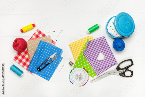 Sewing and home needlework. Composition of bright pieces of cotton fabrics and accessories for sewing on white background. DIY concept. Top view
