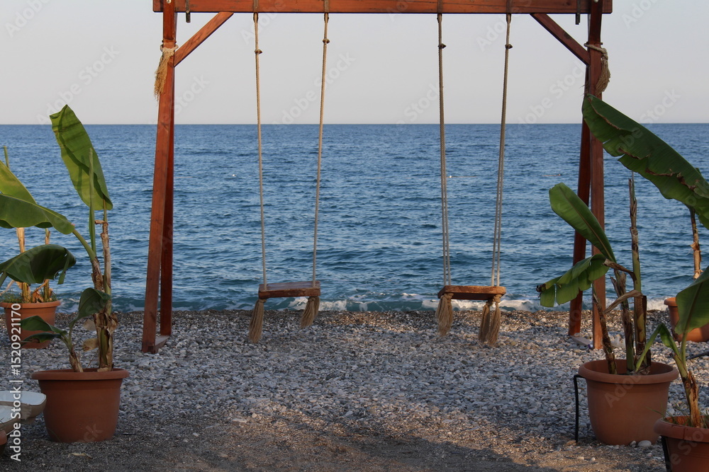 Fototapeta premium swing on a beautiful sea coast, evening beach, mediterranean sea