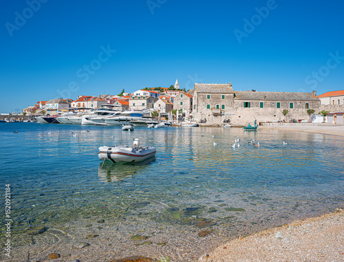Fototapeta Naklejka Na Ścianę i Meble -  A peaceful coastal village in Primosten, Croatia, featuring yachts, stone houses, clear blue water, and a charming Mediterranean atmosphere.