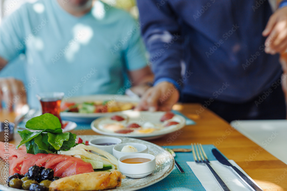 People enjoy a meal together at a sunny restaurant while sharing delicious food People enjoy a meal together at a sunny restaurant while sharing delicious food