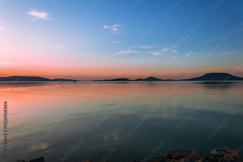 Fototapeta premium Colorful sunset over calm lake and hills 
