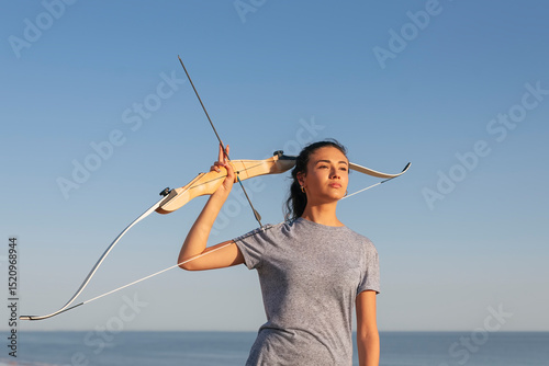 Contemplating young woman holding bow and arrow