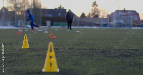 Young athletes practice drills on an outdoor soccer field, using cones to improve their skills