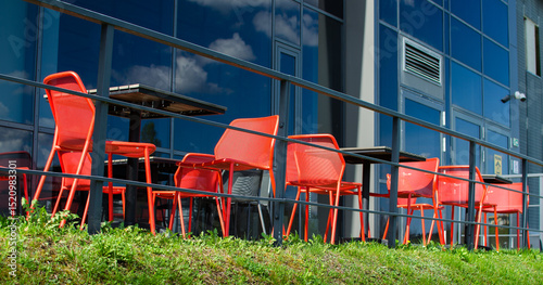 Empty urban café patio with red chairs and black tables