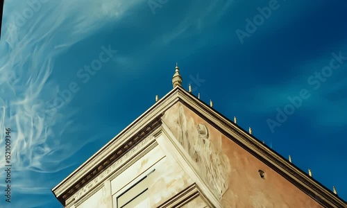 Weathered Stone Building with White Windows Under a Bright Blue Sky and Streaky Clouds During Daytime With Intricate