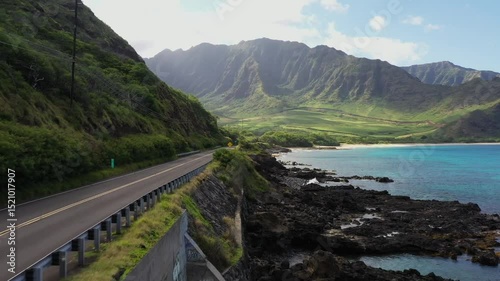 Drone captures scenic coastal road in West Virginia with steep green mountain, clear blue sea, rocky shore, and bright sky, peaceful outdoor view with natural beauty and no human presence photo