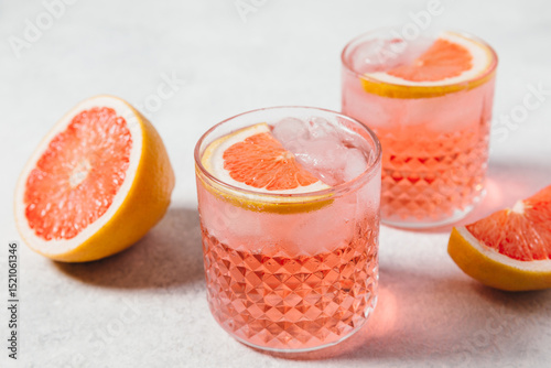 Fotografi A refreshing negroni rosa cocktail served in a textured glass with ice, garnished with a slice of pink grapefruit, set against a light background