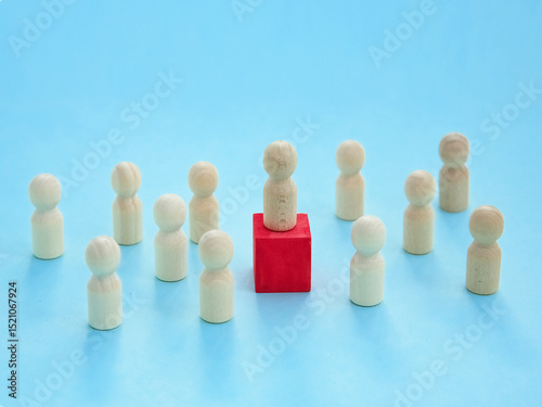 Leader Figure Idea. wooden figures on a blue background. The figure of the leader on a red cube.Connects members. teamwork, community, society