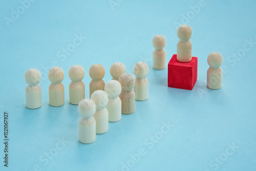 Leader Figure Idea. wooden figures on a blue background. The figure of the leader on a red cube.Connects members. teamwork, community, society