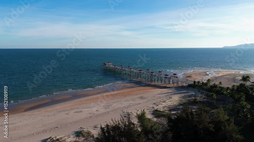 Aerial view of Hamptons pier stretching into calm blue waters from a sandy beach in Ba Ria-Vung Tau