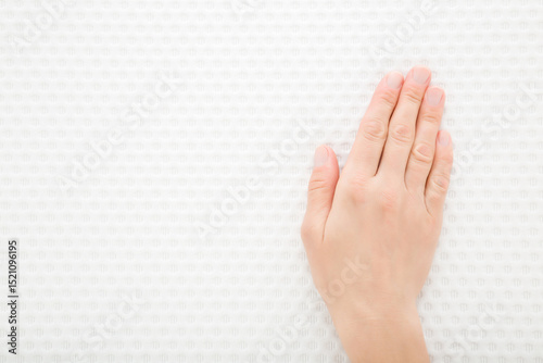 Young adult woman hand touching clean white orthopedic mattress or pillow new cloth material. Checking hardness and softness. Closeup. Top down view.